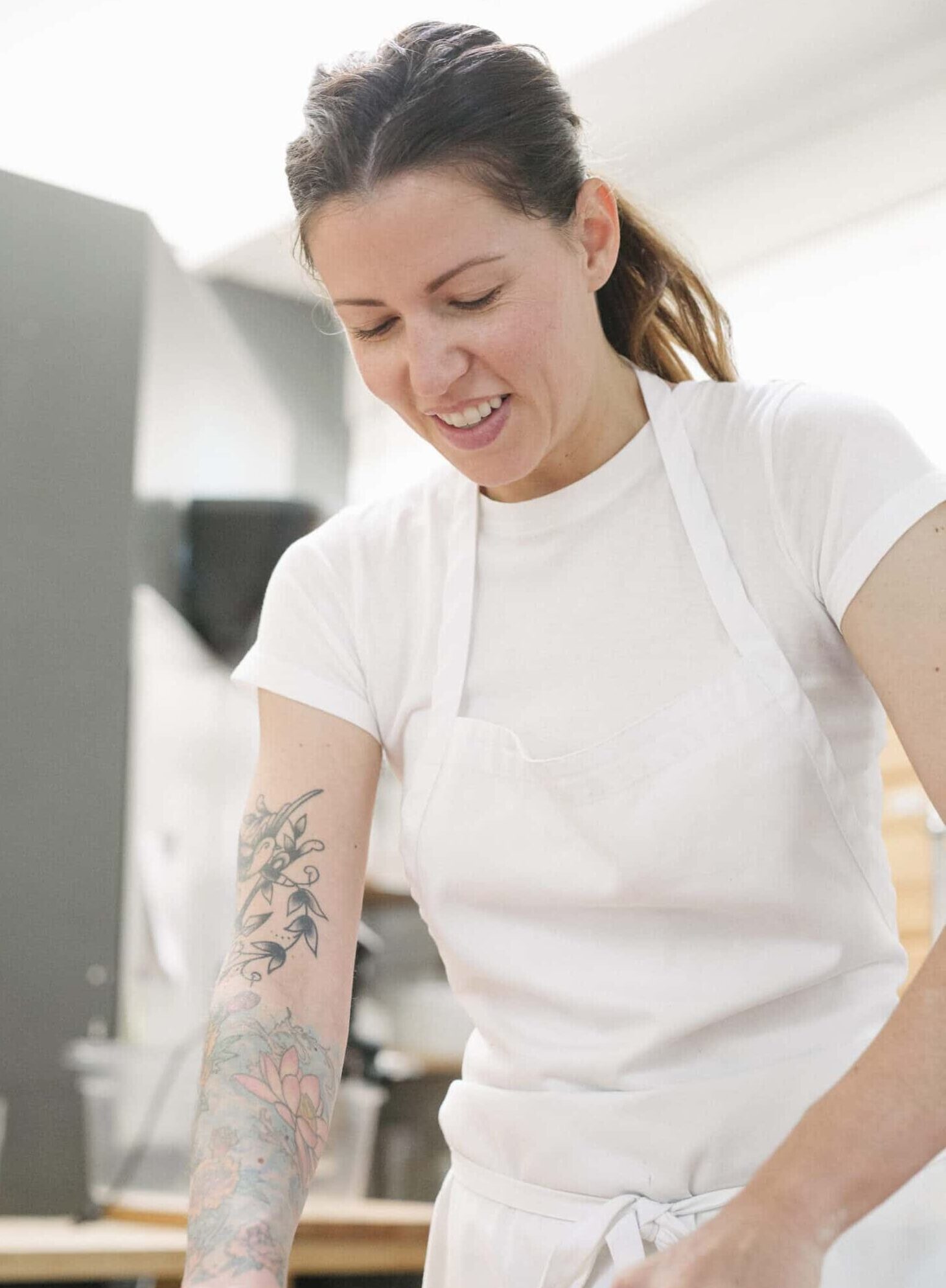 Woman wearing a white apron standing at a work counter in a bakery, chopping chocolate.,Lifestyle,USA
